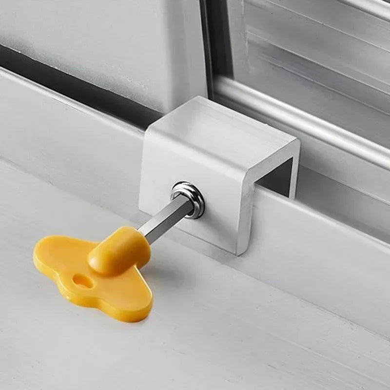 A yellow aluminum alloy sliding window lock with a hex key is installed in a white window frame.