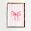 Pink bow canvas print featuring vertical stripes in soft pink and white on a light wood frame.