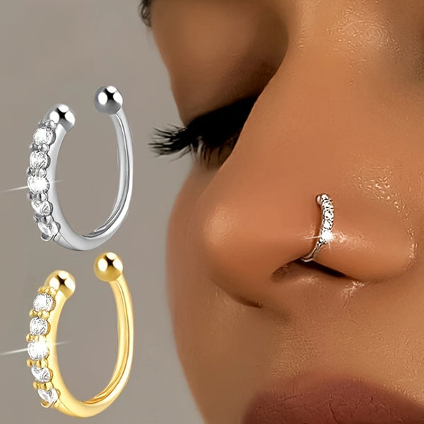A close-up of geometric copper nose cuffs in silver and gold colors shown against a skin tone.