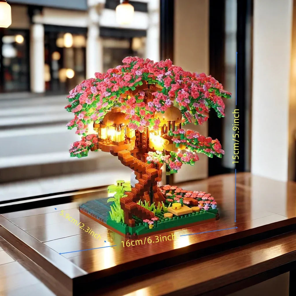 A miniature diorama of a pink sakura treehouse built with wooden blocks and illuminated by an LED light.