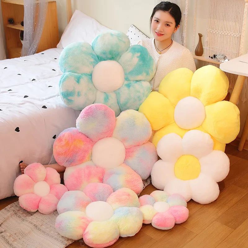 A collection of colorful, lifelike sunflower plush pillows in pink, yellow, and light blue hues.