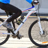 A person riding a white bicycle with black pants and blue shirt, featuring reusable nylon cable ties on the frame.