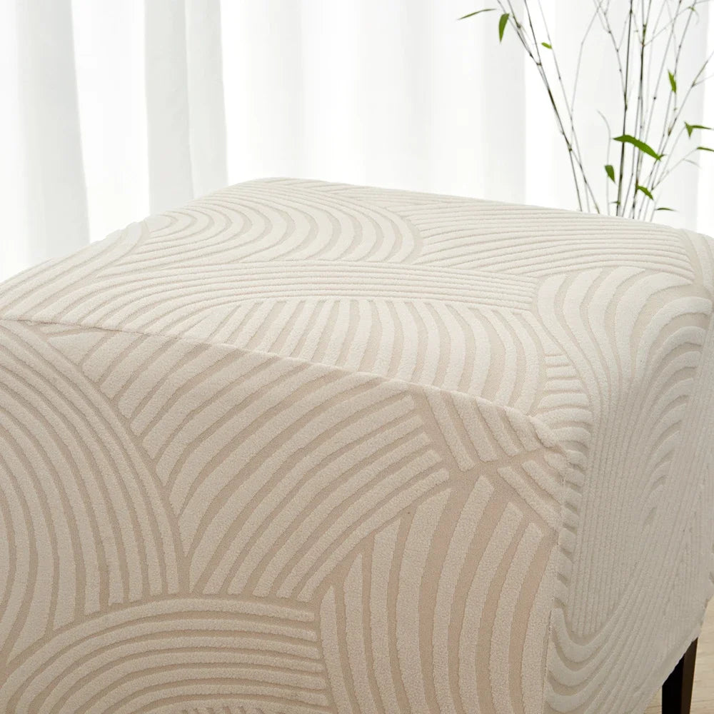 A close-up of a beige geometric jacquard stretch ottoman cover with curved lines.
