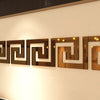 A horizontal display of rectangular acrylic mirror wall stickers with geometric borders mounted on a white wall.