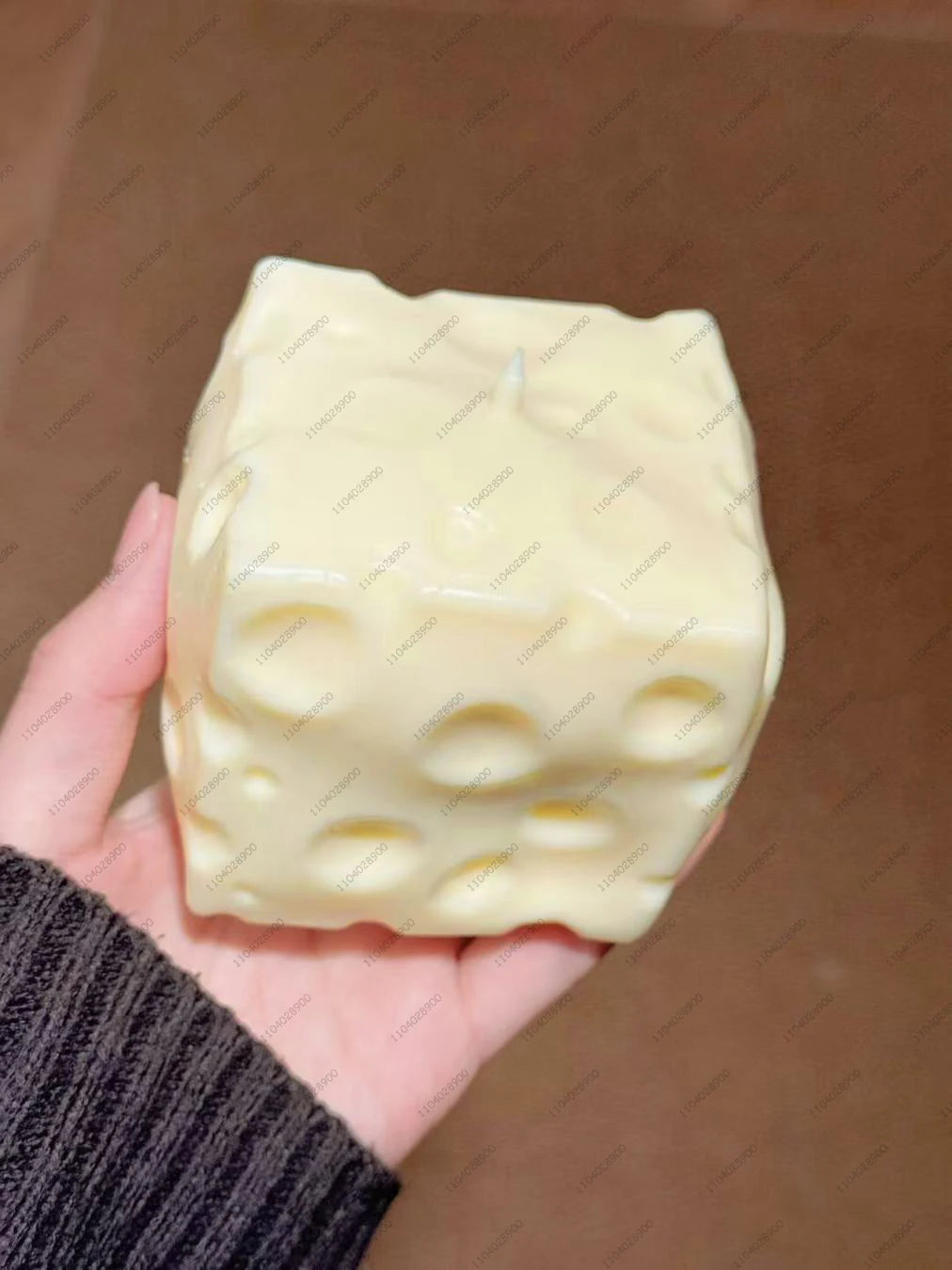 Eine Hand hält einen blassgelben, weichen Kartoffel-Stressball als Fidget-Spielzeug vor einem unscharfen Hintergrund.