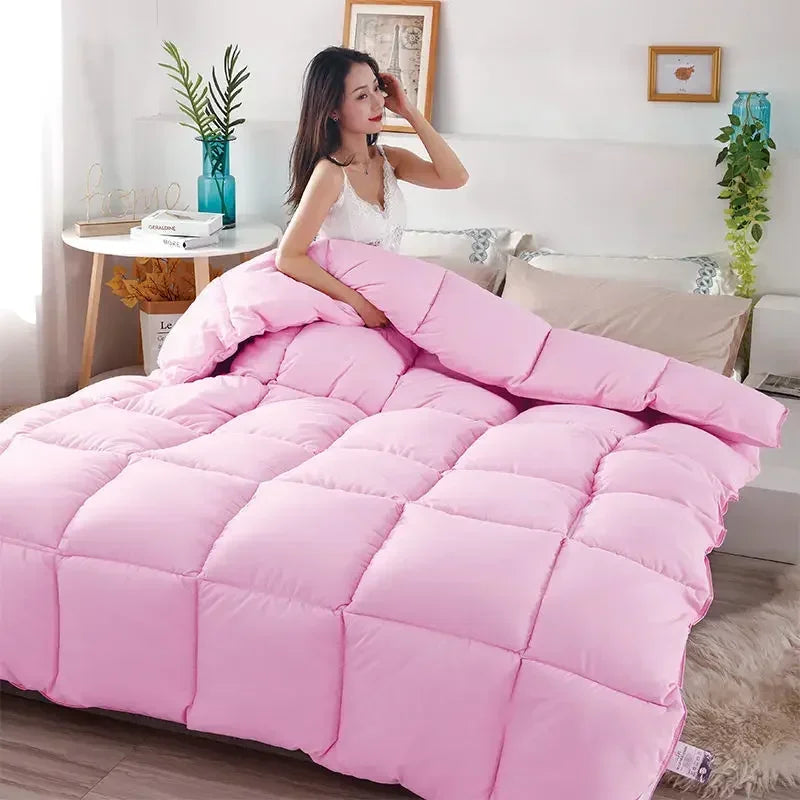 Pink quilted comforter with a cotton cover displayed on a bed.