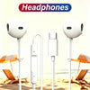 A set of white wired in-ear headphones displayed on a beach with sun umbrellas and lounge chairs.