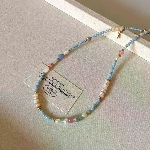 Un délicat collier ras-de-cou, avec une perle et des pierres naturelles bleu, blanc et rose.