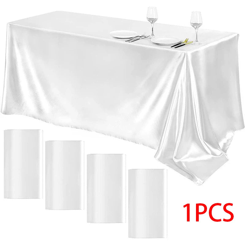 A white satin tablecloth is draped on a table set for formal dining with silverware and wine glasses.