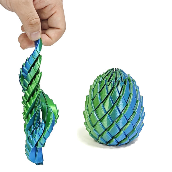 A hand holds a vibrant blue and green expandable dragon egg fidget toy.