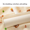 A white roll of soft cotton gauze fabric is shown lying on a light-colored cloth with small animal designs.