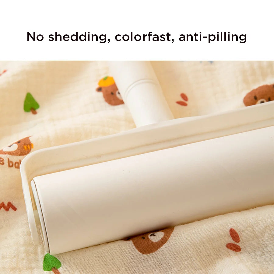 A white roll of soft cotton gauze fabric is shown lying on a light-colored cloth with small animal designs.