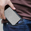 A hand is holding a slim aluminum RFID-blocking pop-up card wallet in a dark brown shirt and blue jeans.