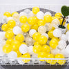 A tray filled with a variety of yellow and white clear plastic ball pit balls for toddlers and kids.