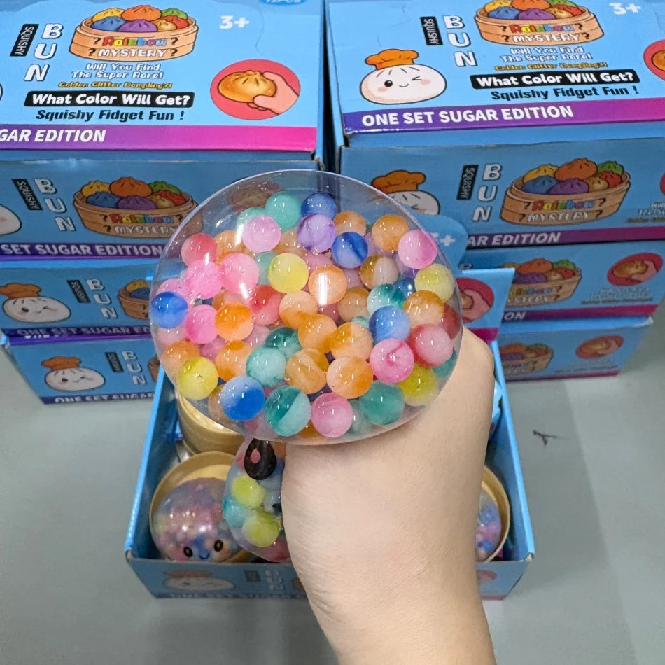 Eine Hand hält eine klare Plastespugel gefüllt mit farbenfrohen Regenbogenperlen, als Squishy-Fidget-Spielzeug.