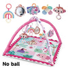 A pink baby play gym mat featuring various hanging toys including a mirror, animal shapes, and colorful fabric items.