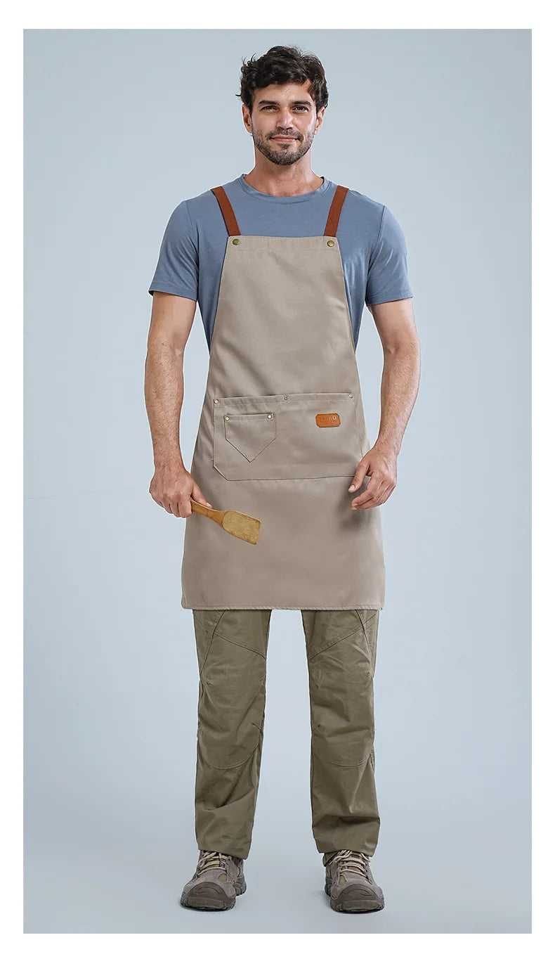A man wearing a beige waterproof kitchen apron over a blue shirt and olive green pants.
