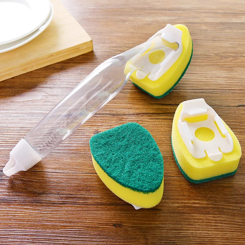 A clear dish wand with a yellow and green sponge head is shown on a wooden surface.