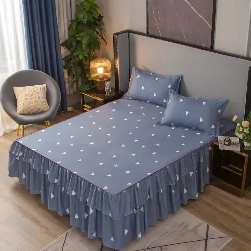 Un lit gris avec une jupe imprimée bleue et des oreillers dans une chambre.