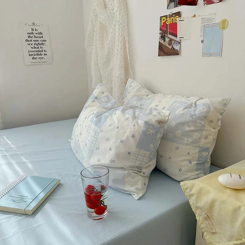 A light blue floral duvet cover set with two matching pillowcases resting on a light blue surface.