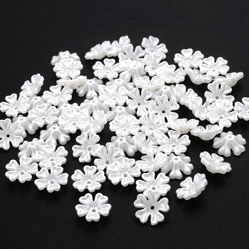 A pile of 100 white acrylic pearl spacer beads shaped like small flowers for jewelry making