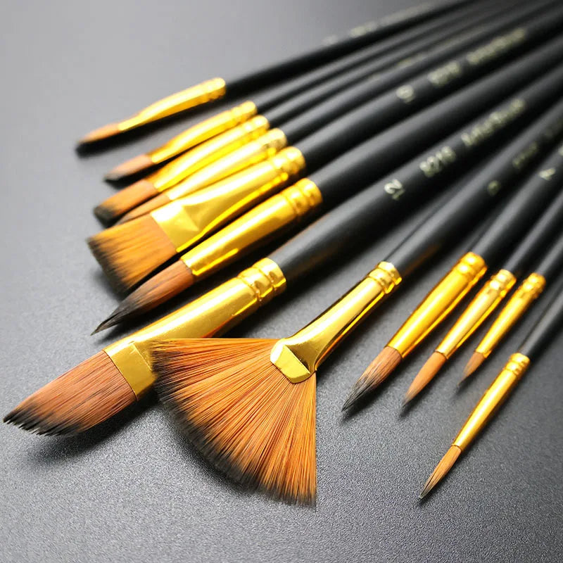 A collection of twelve black and gold nylon bristle flat paint brushes laid out on a dark surface.