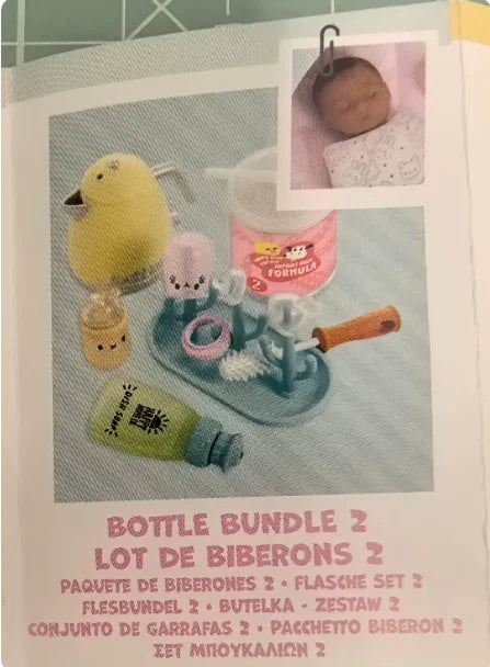 A set of baby bottle accessories including a yellow baby doll, a pink bottle, and various silicone parts.