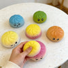 A hand holds a set of colorful squishy stress relief toys, including green, blue, yellow, and orange, on a white table.