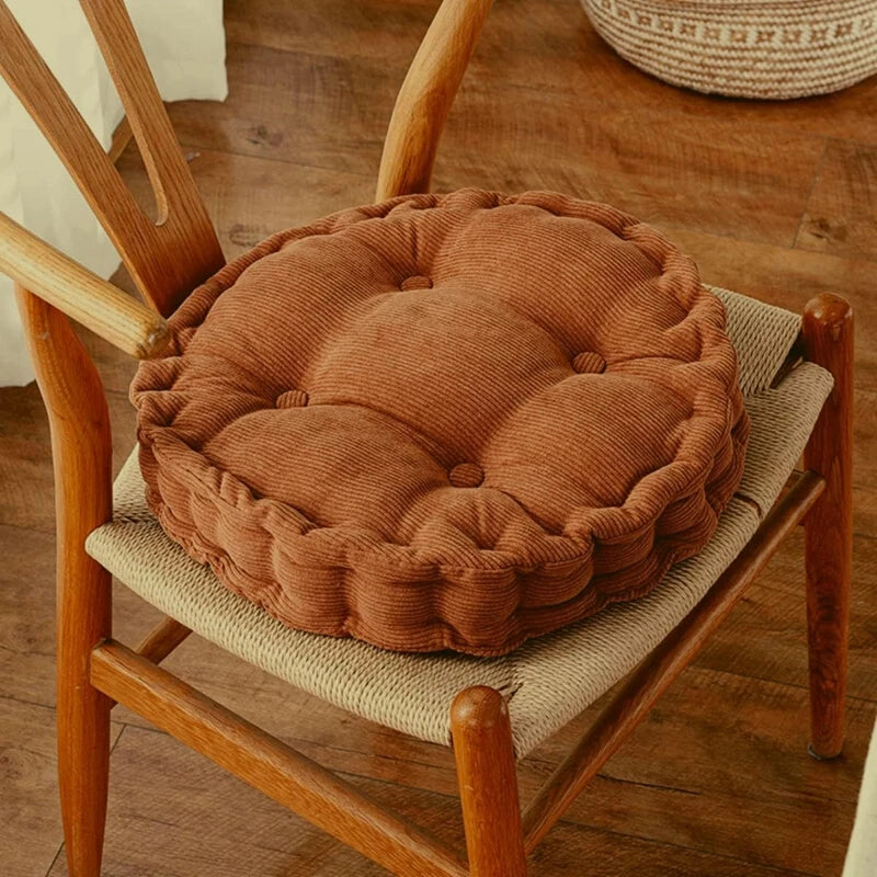 A thick brown corduroy floor cushion is placed on a wooden chair frame.
