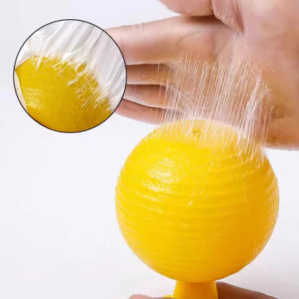 A hand is squeezing a yellow sticky fruit fly trap ball, showing the texture and preparation for pest control.