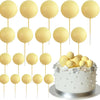 Ein Satz von zwanzig goldenen Ball-Kekstoppern auf Stäbchen in einer Reihe angeordnet.