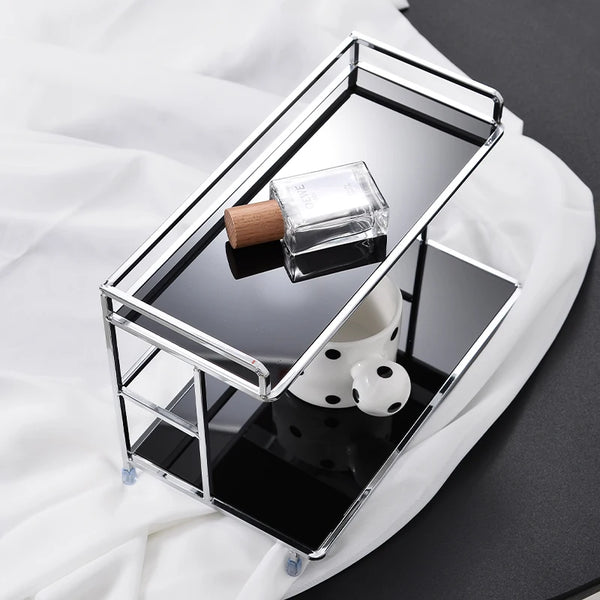 Étagère de bureau métallique à deux niveaux avec un conteneur en verre et un objet sphérique blanc sur une surface noire réfl