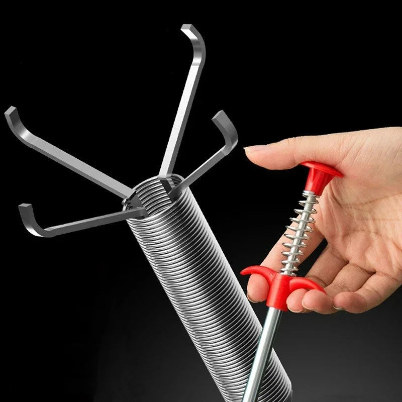 A hand holds a metal drain unclogging tool with an ergonomic handle, showing the tool's design and function.