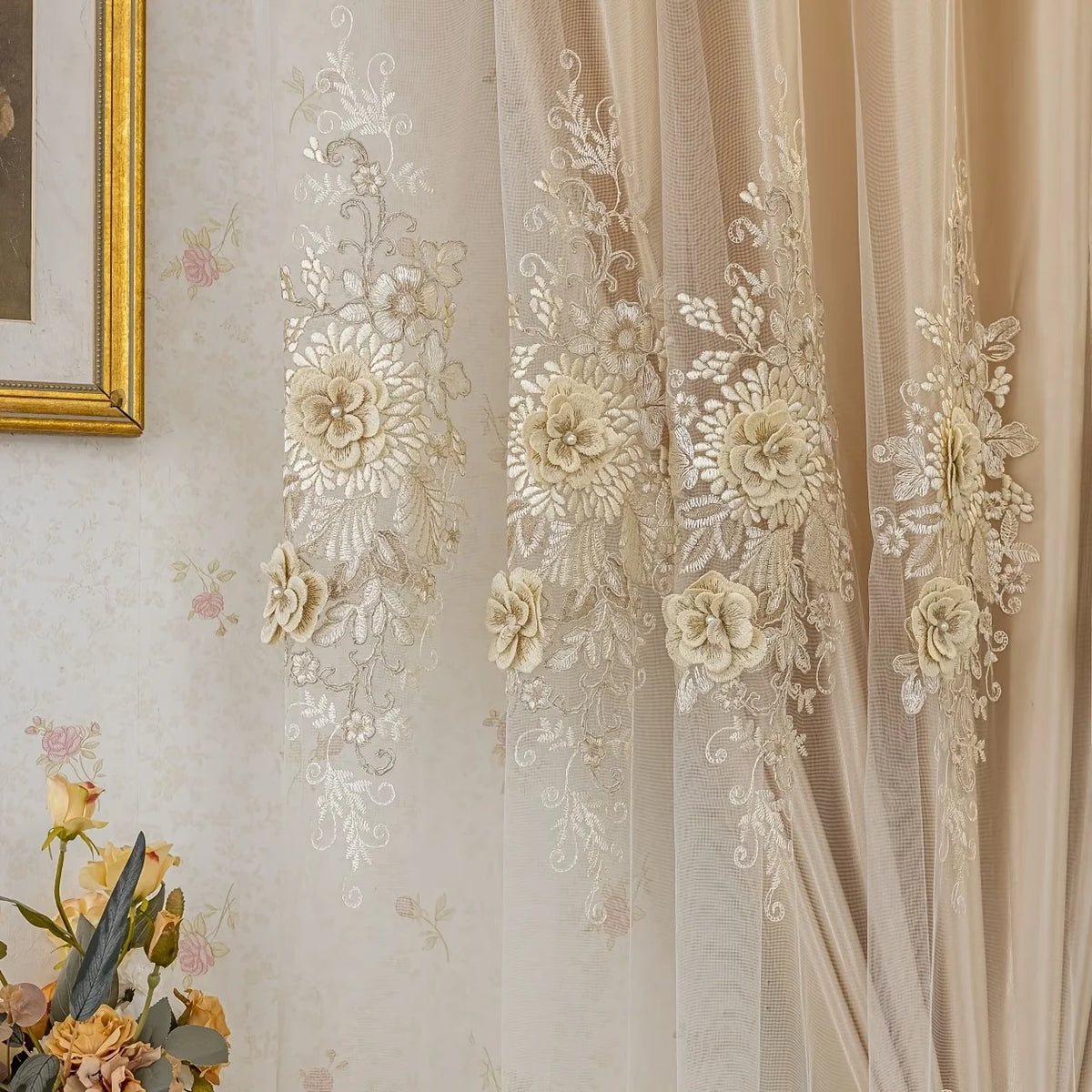 A close-up of a sheer, cream-colored curtain panel featuring delicate white floral embroidery.