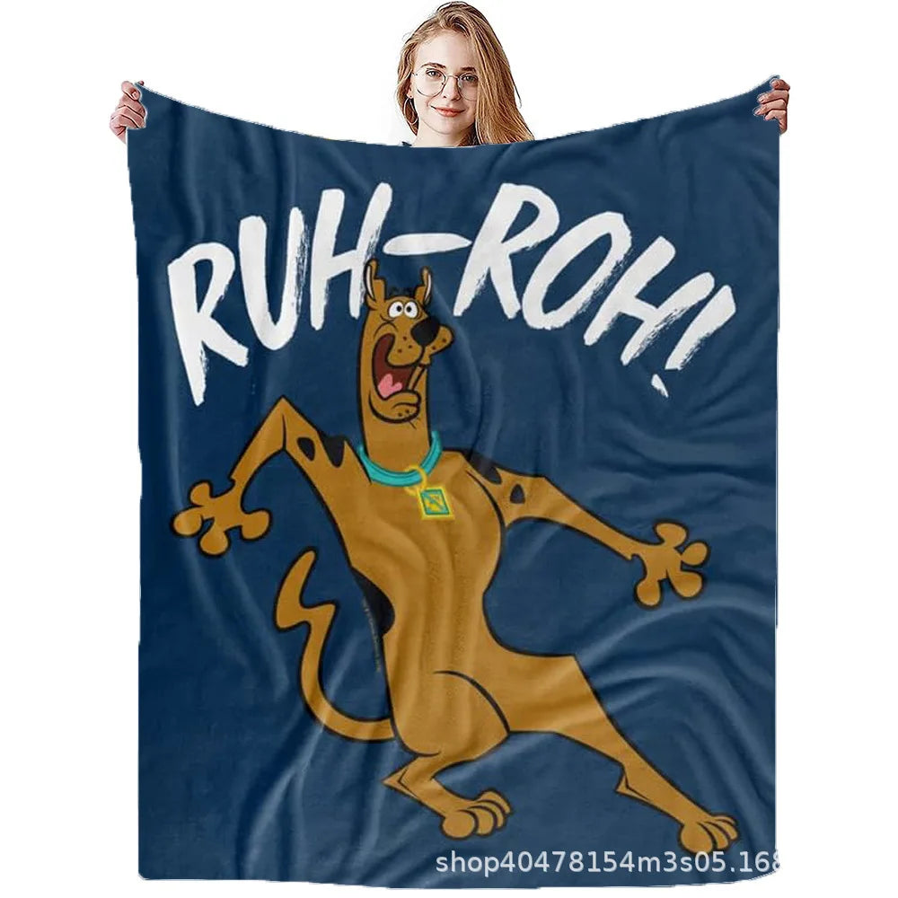 Eine Person hält eine dunkelblaue Flanell-Decke mit einem Cartoon-Hundcharakter und dem Text RUH-ROH hoch.