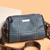 A dark blue vintage genuine leather women's shoulder bag with brown leather strap resting on a light background.