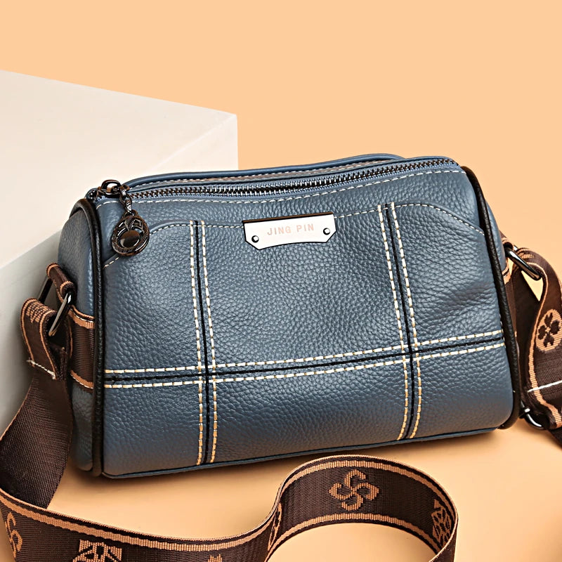 A dark blue vintage genuine leather women's shoulder bag with brown leather strap resting on a light background.