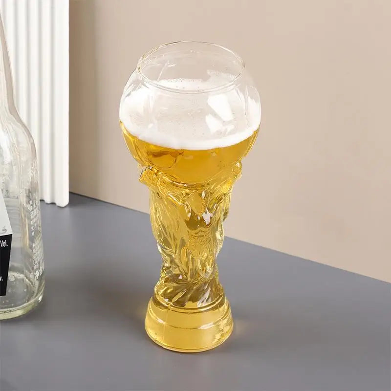 Goldene Pokal-ähnliche Biermaß mit blassem gelbem Bier und weißem Schaum auf grauem Untergrund.