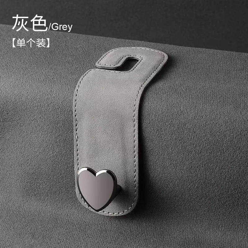 A grey car seat headrest hook with a heart-shaped dual hook for securing bags or phones.