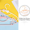 A set of adjustable baby clothes hangers in pink and white plastic are displayed on a yellow background.