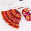 A close-up of a knitted hat in gradient colors featuring red, orange, and yellow yarn.