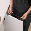 A person is installing a black punch-free over-cabinet towel rack onto a white cabinet door.