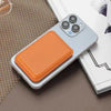 An orange magnetic leather wallet case with a kickstand is shown resting on a beige surface next to an iPhone.