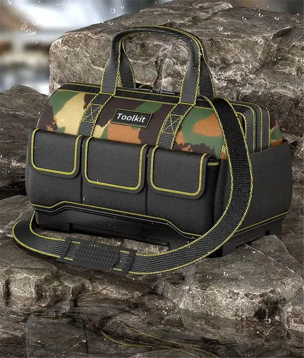 A black heavy-duty camouflage tool kit bag with a reinforced base and yellow trim, resting on dark rocks.