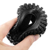 A hand holds a black mud terrain rubber tire for RC crawlers.