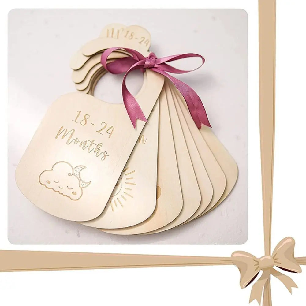 Wooden baby closet dividers with light wood labels and pink ribbon tied on the top