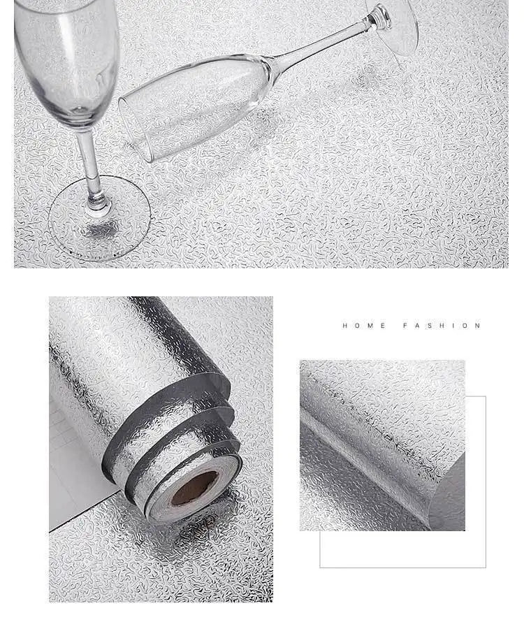 A glass wine glass is shown next to a roll of brushed silver peel-and-stick metal wallpaper.