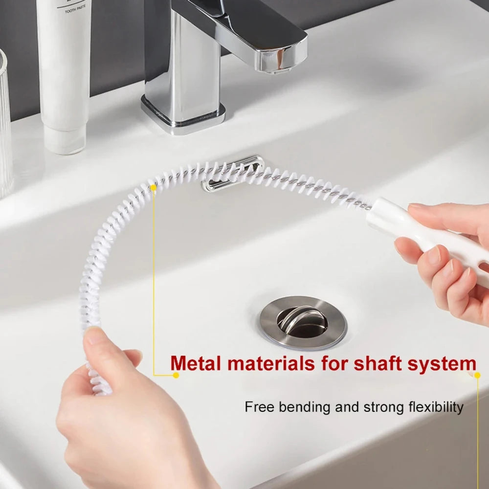 A hand is holding a flexible metal brush with a coiled shaft system over a white sink, demonstrating its bending and flexibil