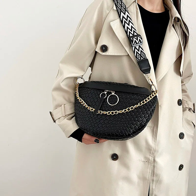 A beige trench coat features a black woven pattern waist bag with a gold chain strap.