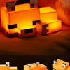 A fox-shaped night light with a warm orange glow resting on a dark surface.